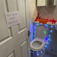 a white toilet sitting in a bathroom next to a christmas light decoration on the wall