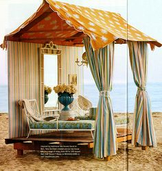 a bed sitting on top of a sandy beach next to the ocean in front of a tent