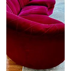 a large red couch sitting on top of a wooden floor next to a rug and table