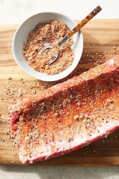 a piece of steak on a cutting board with seasoning in a bowl