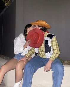 a man and woman are kissing while sitting on a bench with a cowboy hat on their head