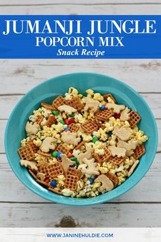 a blue bowl filled with cereal next to a white wooden background and text that reads, jumani jungle popcorn mix snack recipe