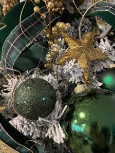 green and gold ornaments are on top of the christmas tree