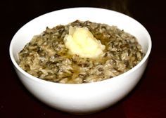 a white bowl filled with oatmeal topped with a piece of butter on top