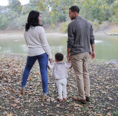 a man and woman holding hands while standing next to a small child