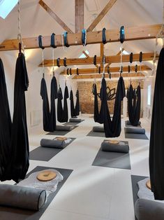 a room filled with yoga mats covered in black cloths and hanging from the ceiling