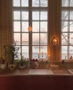 a kitchen counter topped with lots of pots and pans filled with food next to large windows