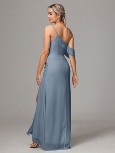 a woman in a long blue dress with one shoulder and open back, looking to the side