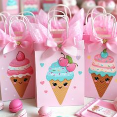 small pink bags decorated with ice cream and cupcakes are sitting on a table