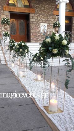 candles are lined up in front of a building with flowers and greenery on it