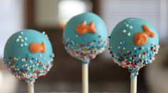 three cake pops with blue frosting and sprinkles are on a table