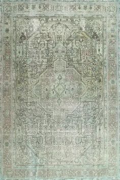 an antique rug with green and beige colors