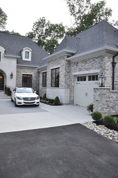 a white car parked in front of a large house with two garages on each side