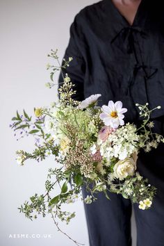 a person holding a bouquet of flowers in their hands and wearing a black shirt behind them