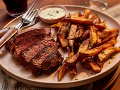 a steak and french fries on a white plate