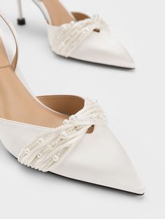 a pair of white shoes with pearls on the heel