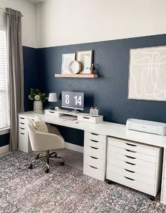 a white desk with drawers and a printer on it in a room that has blue walls