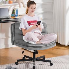 a woman is sitting in an office chair and looking at her phone while wearing pajamas