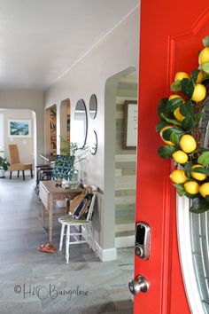 a red door with some lemons hanging on the side and a mirror behind it