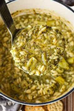 a ladle full of broccoli and rice soup with crackers on the side