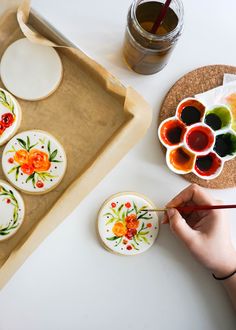 a person is painting decorated cookies on a tray with paintbrushes and watercolors