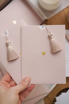 two cards with tassels are being held up