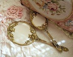 two mirrors sitting on top of a bed next to a pink flowered pillow and pillows