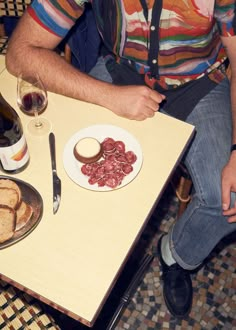 a man sitting at a table with food and wine