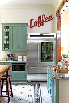 a kitchen with green cabinets and stainless steel appliances, including a coffee maker on the wall