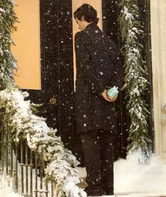 a woman standing in front of a door covered in snow