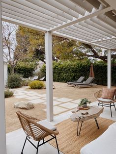 an outdoor patio with chairs and tables on the floor, surrounded by shrubs and trees