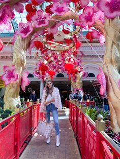 a woman walking down a walkway with pink decorations on the ceiling and red railings