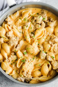 a pot filled with pasta and meat in sauce on top of a white table cloth