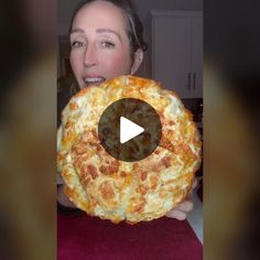 a woman holding up a giant pizza in front of her face and making a funny face