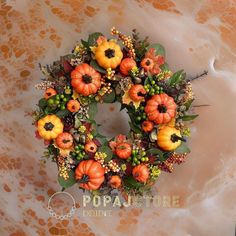 a wreath with pumpkins and other flowers on top of a marble slabd surface