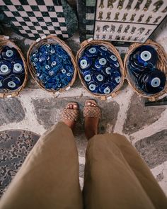 a person standing in front of baskets filled with blue glass beads and bottles next to each other