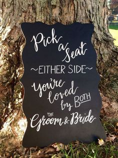 a sign that says pick a seat, either side you're loved by both the groom and bride