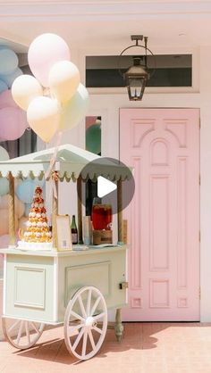 an ice cream cart with balloons in front of a pink door