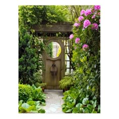 a garden with lots of plants and flowers around it, including a small wooden door