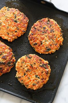 four crab cakes sitting on top of a black pan