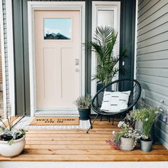 a porch with potted plants on the front steps and a door in the background