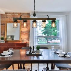 a dining room table and chairs with lights hanging from the chandelier over it