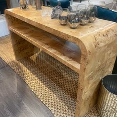 a wooden table with glasses on it in front of a blue couch and other furniture