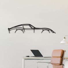 a desk with a laptop on it next to a wall mounted car shaped art piece