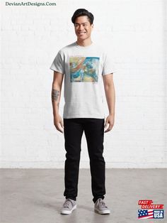 a man standing in front of a white brick wall wearing a t - shirt with an image of a mermaid on it