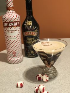 a martini cocktail with candy on the table next to it and two liquor bottles in the background