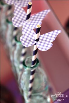 two paper birds are sitting on top of each other in glass jars with striped straws