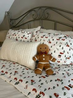 a gingerbread man sitting on top of a bed with white sheets and pillow cases