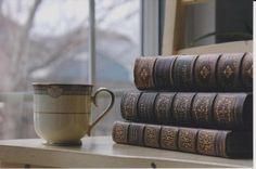 a stack of books sitting on top of a table next to a coffee cup