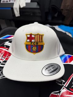 White 5 Panel Snapback Hat , with the Fc Barcelona Logo embroidered on the front White Trucker Hat With Flat Bill For Fan Merchandise, White Flat Bill Trucker Hat For Fans, White Flat Brim Baseball Cap With Logo Patch, White Custom Logo Snapback Hat For Sports, White Custom Logo Snapback Hat For Sports Events, White Snapback Hat With Custom Logo For Sports, White Baseball Hat With Embroidered Logo, White Snapback Baseball Cap For Fans, White Fitted Baseball Cap With Logo Patch